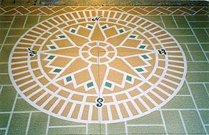 A stencil was used to create this colorful compass surrounded by a stenciled brick patterned floor by Stencil Systems