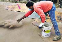 Throwing color hardener onto a fresh concrete slab prior to stamping or texturing the concrete.