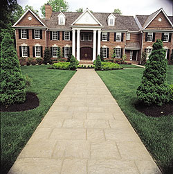 A long stamped concrete walkway that leads to the front entrance of an expansive home.