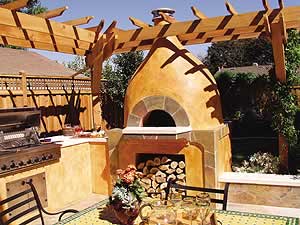 An outdoor Mexican style concrete kitchen with a dome type pizza oven and a pergola surround.