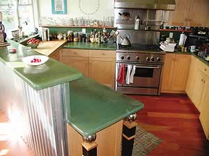 Beautiful green gray concrete countertops in a kitchen with corrugated metal bar backing and red hardwood floors.