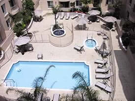Rectangular pool with inward rounded corners surrounded by a light colored Versatile Building Products coated pool deck.