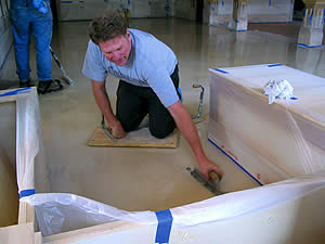 Contractor uses a trowel on a white concrete floor to create the look he is after