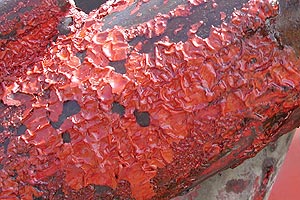 Red paint that is chipping and bubbling off of metal.