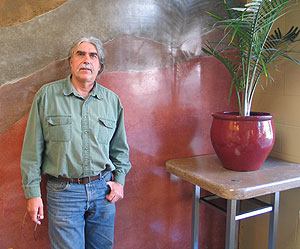 Water Bros. Construction's Ken Froebig standing next to a high side table made from concrete and a vertical sediment layered look concrete wall.