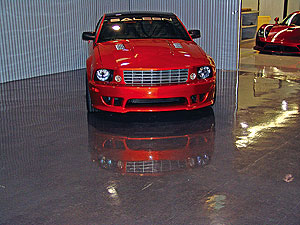 Red Ford Mustang in a auto show room whose floor is a slick shining concrete floor coating.