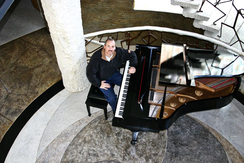 Vince Schrementi of Everlast Concrete sitting at a piano surrounded by beautifully stamped concrete floors. 