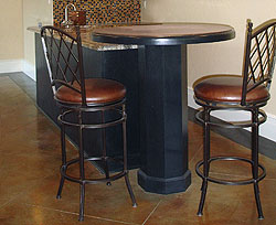 Concrete countertops sit atop a cylinder like base post over stained and engraved concrete floors.