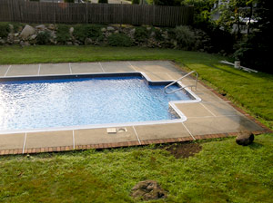 Pool deck that is surrounded by bright green grass.