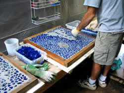 Placing blue glass pieces into the concrete one by one to create the mosaic look of the ocean