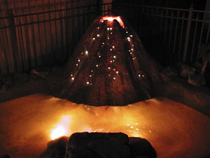 A volcano that looks like lava is oozing from it is achieved with concrete and fiber optics.