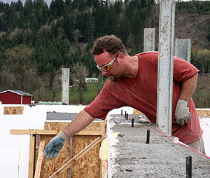 Concrete specialist Justin Farley reaches for a mag float to smooth the top of the concrete homes exterior walls.
