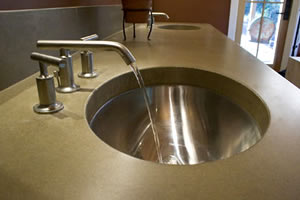 Dual stainless steel under-mount sink beneath a matte finish concrete countertop.