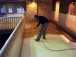 A contractor with a mask sprays the stain onto the concrete floor.