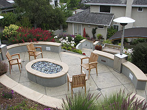 A perfect sitting area was created on the upper deck of this concrete patio with the firepit and wood chairs.