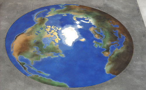 Stained concrete in the shape and colors of the world with blue ocean and browns and greens for topography.