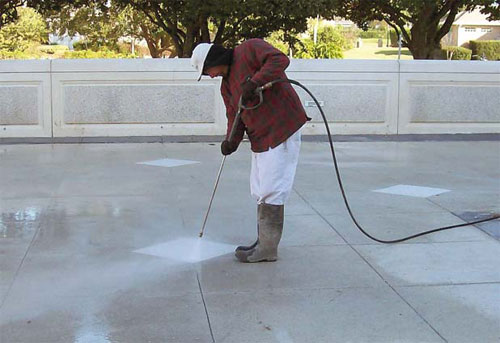 Workers apply retarder, cut with a soft-cut saw and a decorative beveled edge blade, and pressure-wash to expose aggregate in the new walkway.