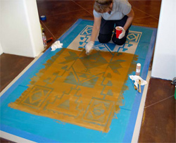 Applying the stain to the stencil before removing it.